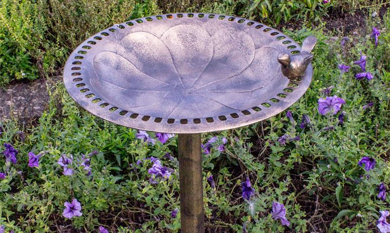 Copper effect plastic resin bird bath on a stand