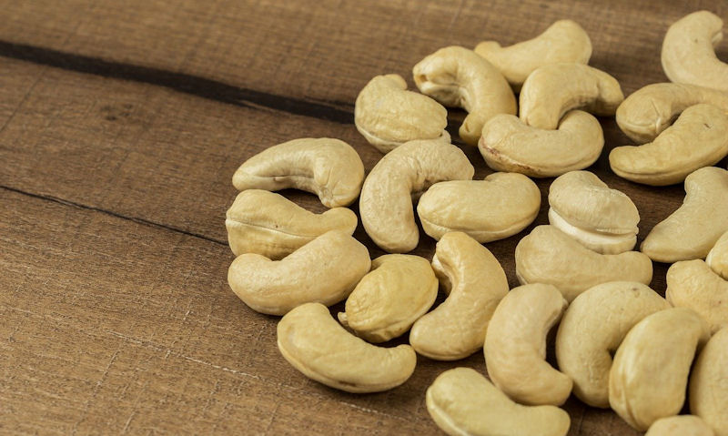 Unsalted cashew nuts piled on rustic wooden board